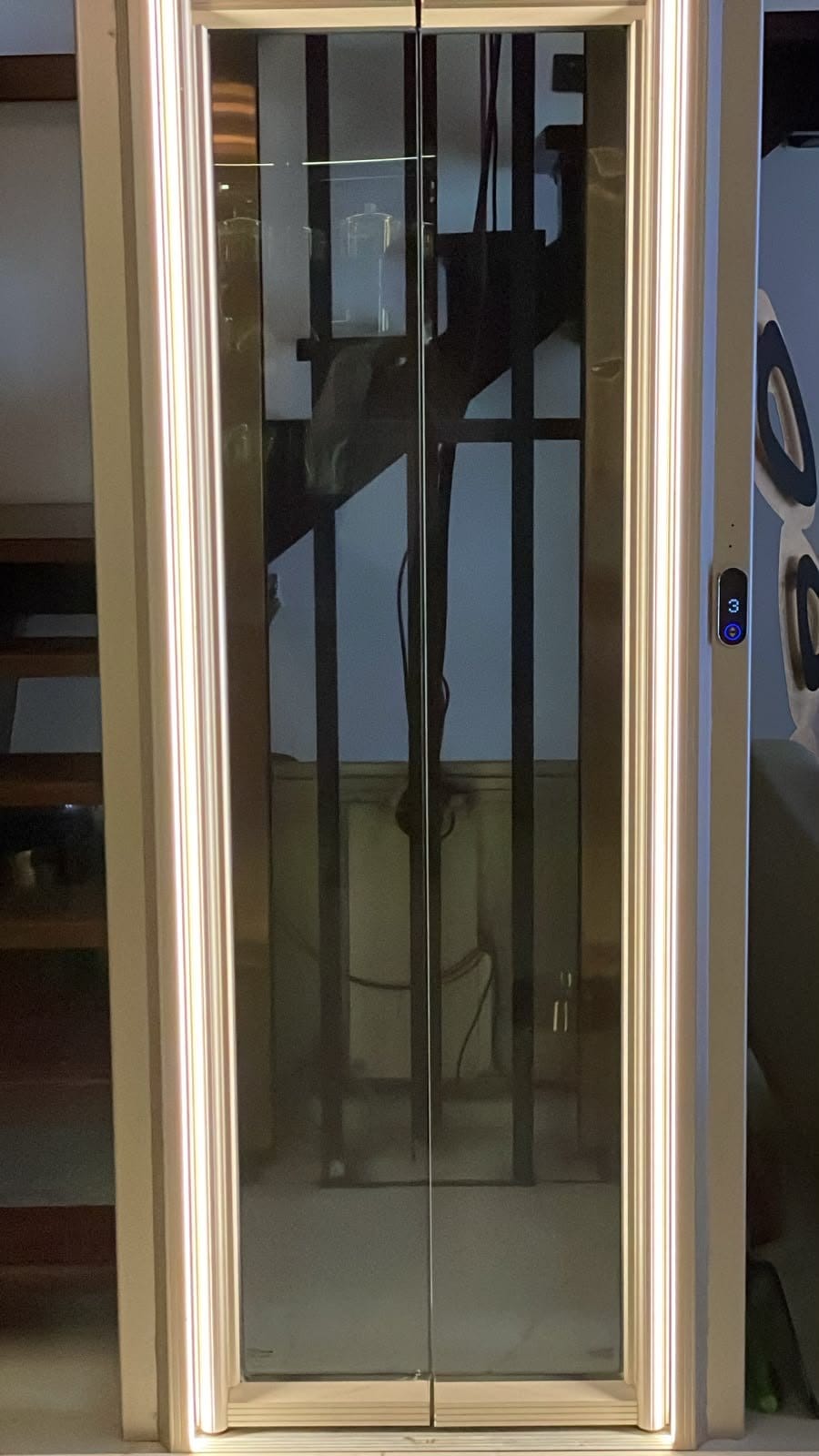 The client’s lift: its glass landing doors closed in a frame of warm LED strips