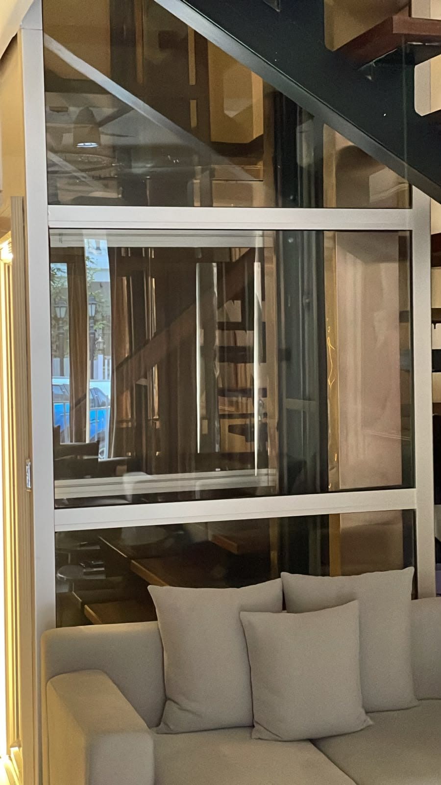 The glass shaft from the side, beside the living-room sofa